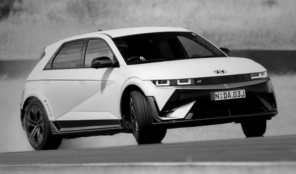 A very sideways Ioniq 5 N on a racetrack surface with scrubby grass in the background